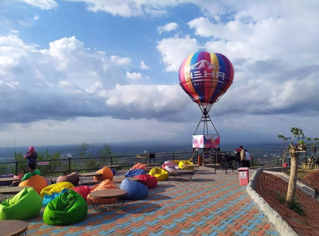 Balon udara berwarna cerah di atas area bersantai dengan bangku empuk, menawarkan pemandangan indah dari ketinggian.