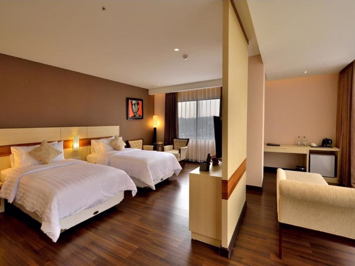 Kamar hotel modern dengan dua tempat tidur, dekorasi minimalis, dan area santai yang nyaman untuk pengalaman menginap yang menyenangkan.