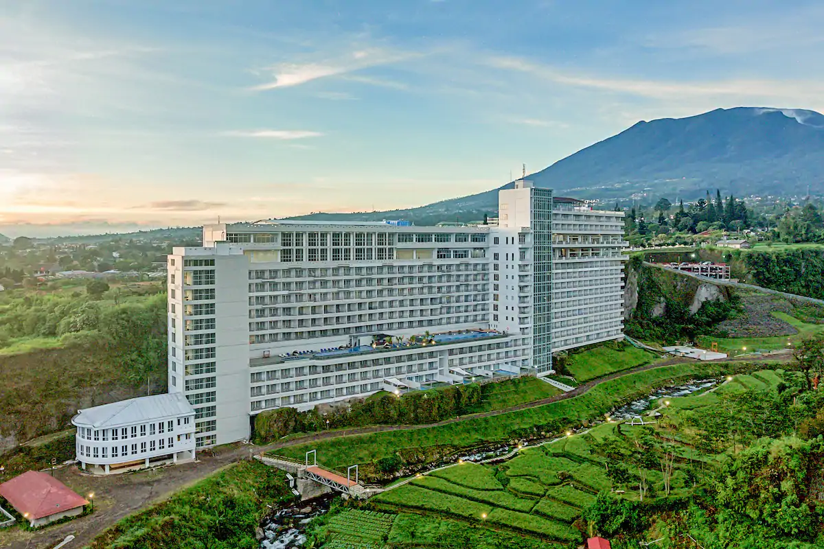 Hotel modern dengan pemandangan pegunungan, dikelilingi kebun hijau dan aliran sungai, ideal untuk liburan santai.