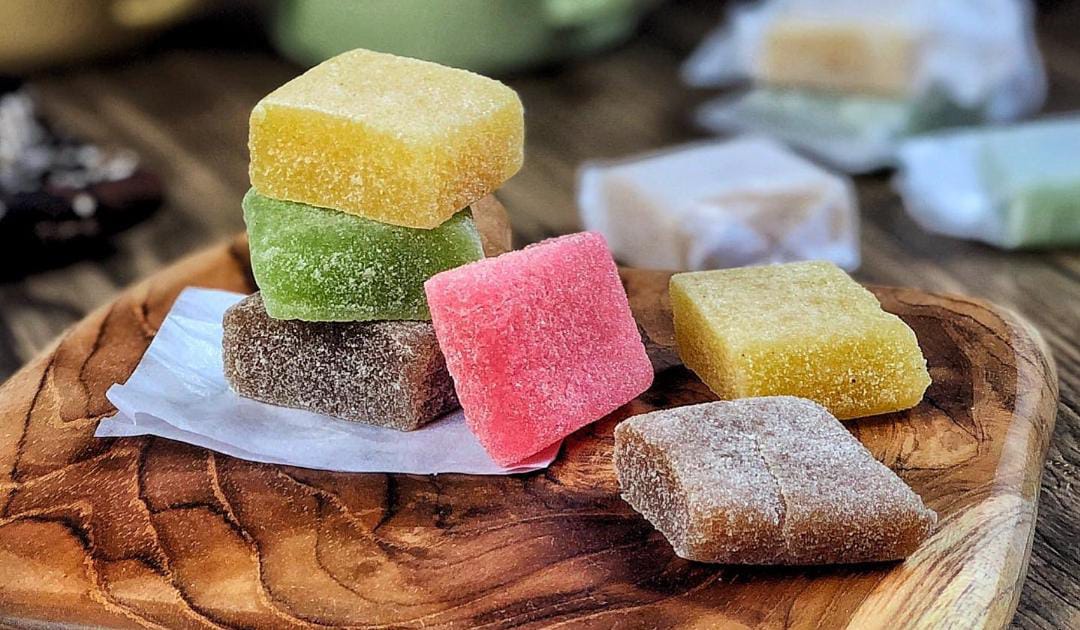 Camilan tradisional manis berwarna-warni yang menyegarkan, disajikan di piring kayu alami.