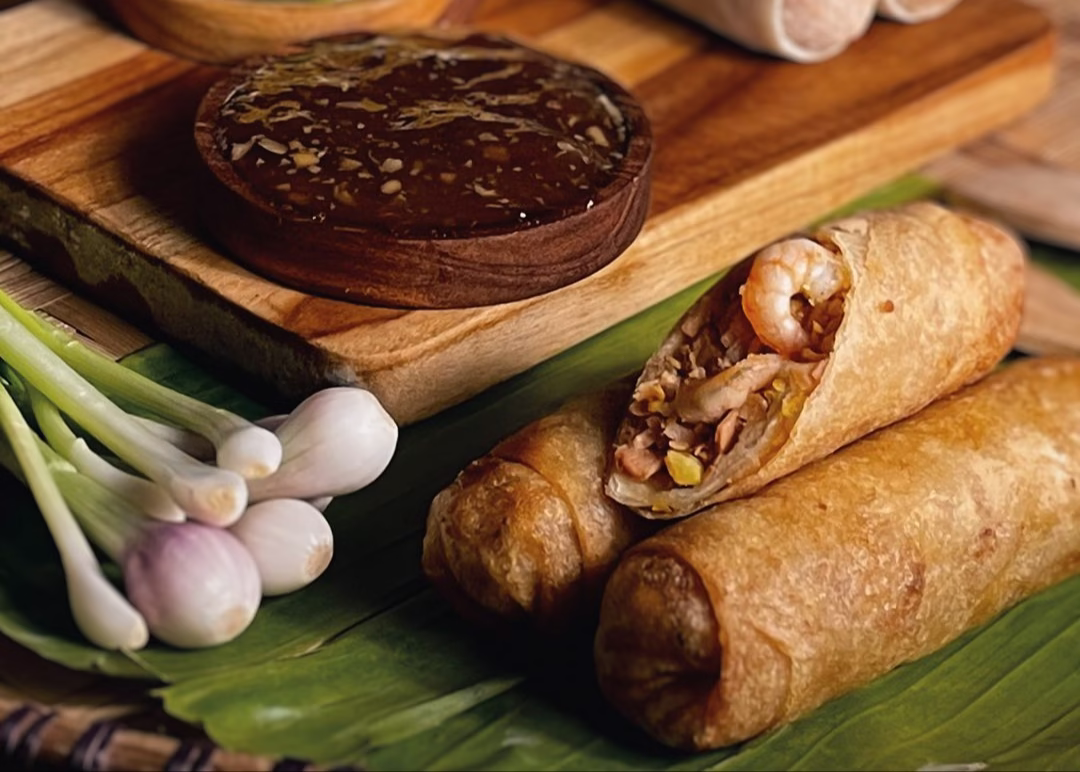 Spring roll filled with shrimp and vegetables served with a rich, savory sauce and garnished with fresh scallions.