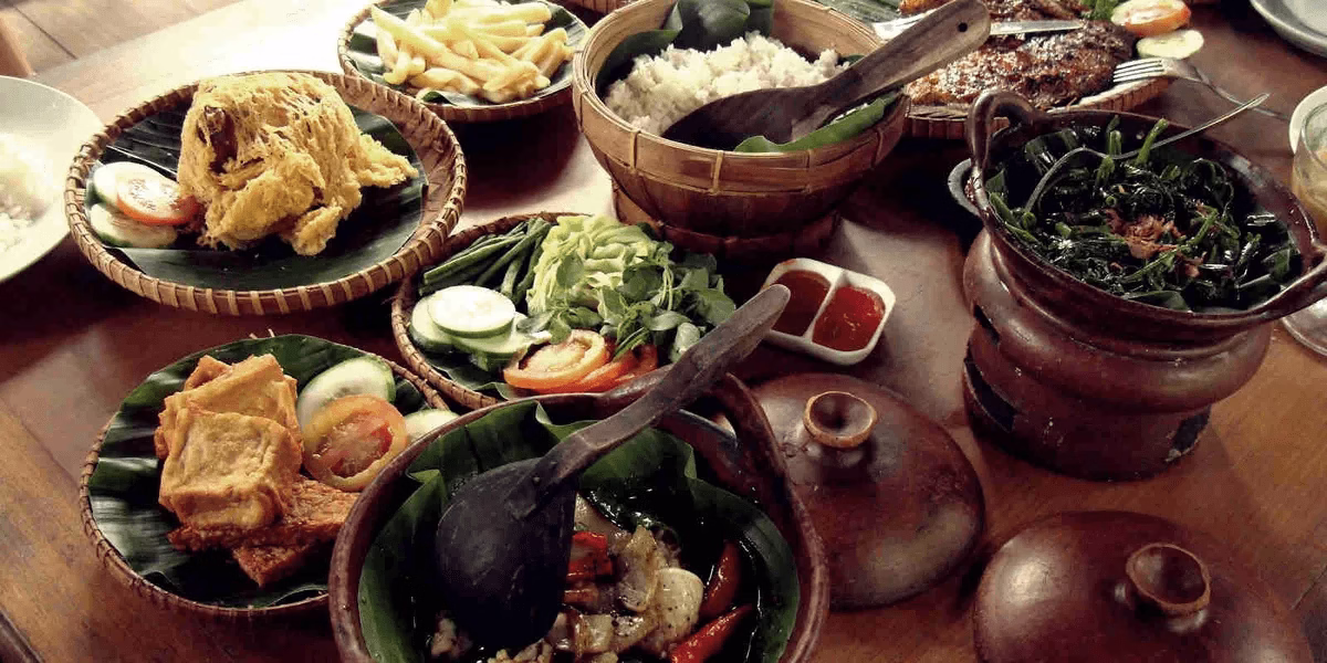 A traditional Indonesian feast featuring vibrant dishes like fried tofu, fresh vegetables, and delicious rice on banana leaves.