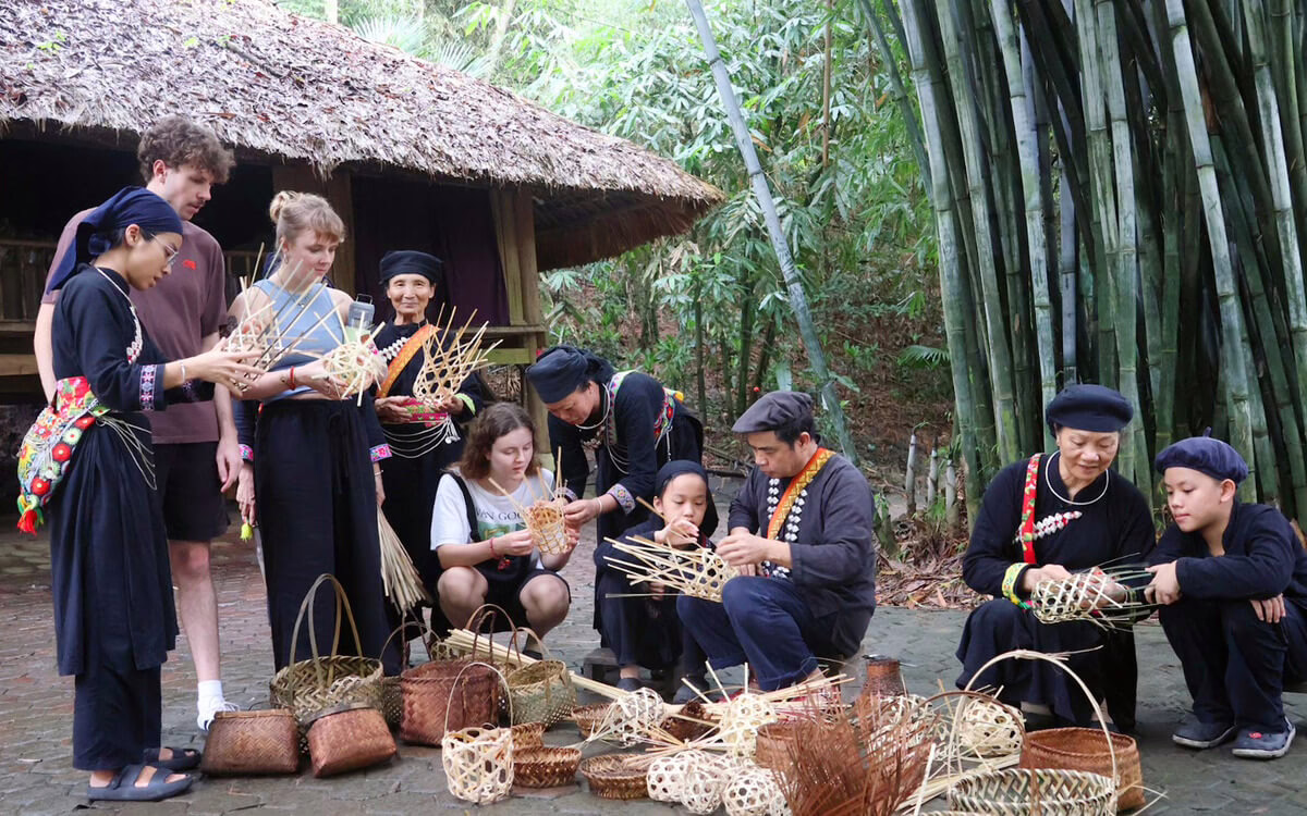 Kelompok pelajar belajar membuat keranjang anyaman di komunitas lokal, menghadirkan seni dan budaya tradisional di Desa Wisata Thái Hải, Vietnam