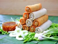Lumpia goreng renyah disajikan dengan saus sambal dan sayuran segar, menciptakan hidangan yang menggugah selera.