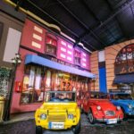 Kota miniatur dengan mobil klasik warna-warni di depan restoran Prancis yang memukau dan suasana yang penuh pesona.