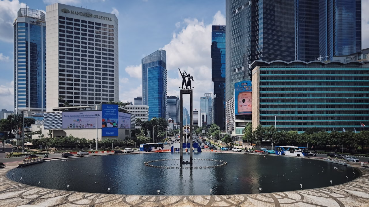 A cityscape shows modern buildings around a statue.