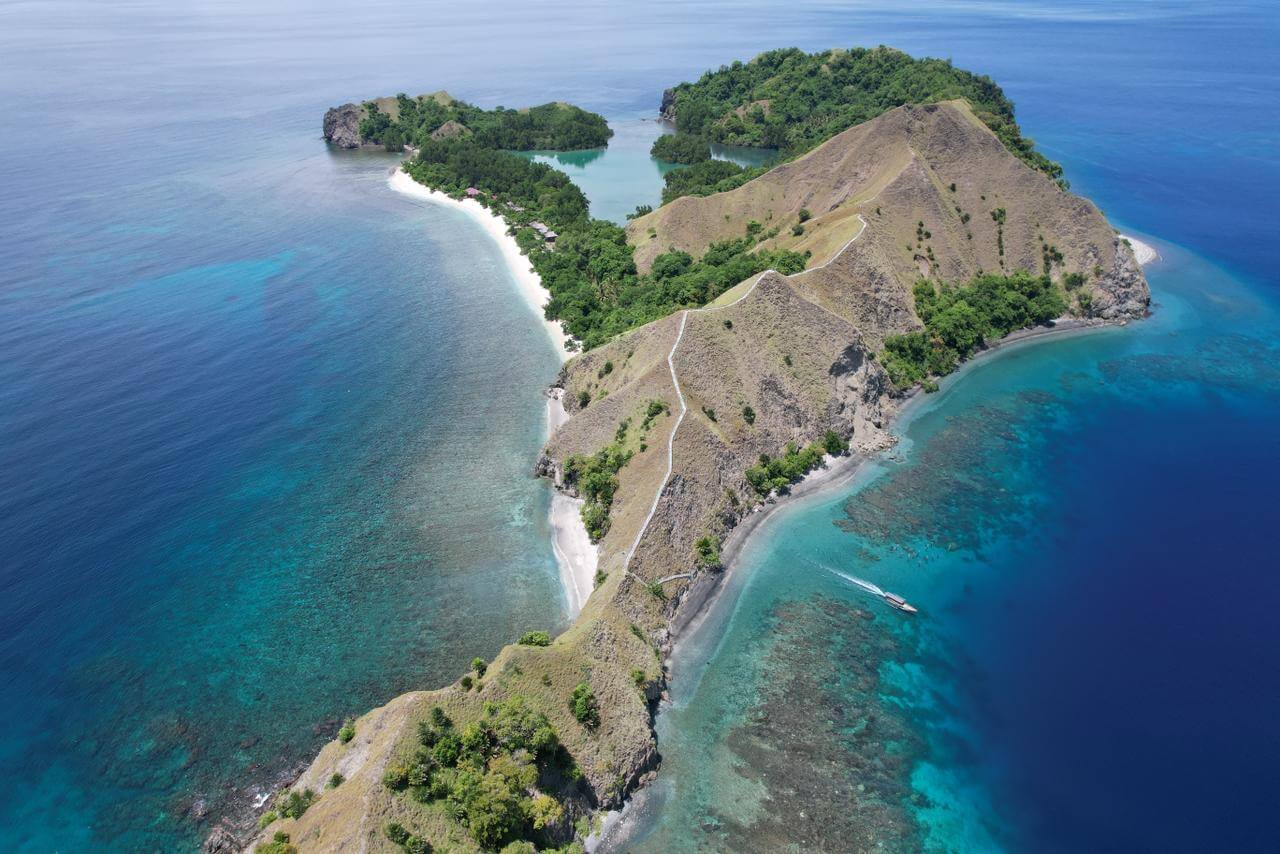 Pemandangan pulau tropis indah dengan pantai berpasir putih dan air laut jernih, ideal untuk petualangan dan bersantai.