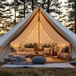 Tenda glamping berhiaskan lampu hias, menyuguhkan kenyamanan dengan sofa dan tanaman hijau di tengah hutan yang tenang.